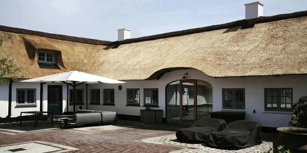 Thatched-roof courtyard house with arched glass entry